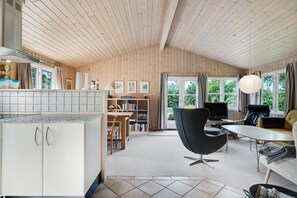 A modern kitchen with wooden cabinets and a dining area with a black chair and a sofa.