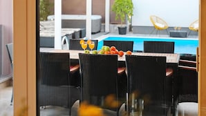 An outdoor dining area with wicker chairs and a table set with fruits and drinks, overlooking a swimming pool. - Awesome home in Nin with sauna (Nin)