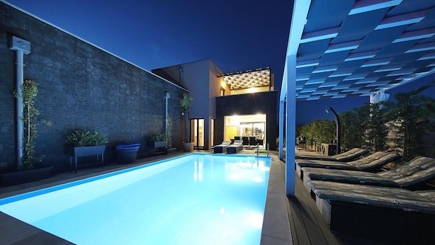 A swimming pool with lounge chairs, a brick wall, and a pergola. - Awesome home in Nin with sauna (Nin)