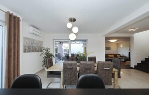 Un espace repas moderne avec une table et des chaises en bois, une plante en pot et une vue sur le salon adjacent.