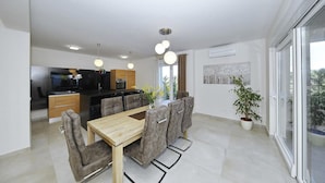 A modern kitchen with a built-in oven and a dining area with a wooden table and grey upholstered chairs. - Awesome home in Nin with sauna (Nin)