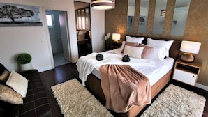 A modern bedroom with a large bed, bedside lamps, a mirror, and a painting of a tree. - Awesome home in Nin with sauna (Nin)