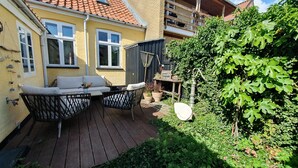 Une terrasse avec des meubles d’extérieur, un robinet et une clôture en bois.