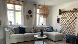 Un salon comprenant un canapé, une table basse ronde, un luminaire en fibres tressées, un mur ajouré et une plante en pot.