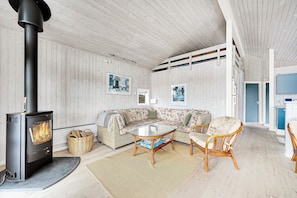 A cozy room with a wood-burning stove, a sofa, wicker chairs, and a glass coffee table.