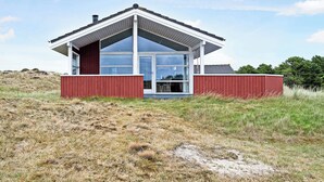 Een modern huis met een groot raam, een rode gevel en een wit dak.