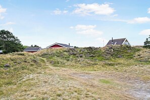 A rural landscape with two houses on a hill, a clear sky, and a dirt path. - Holiday house on Fanø near the sea (Fanø)