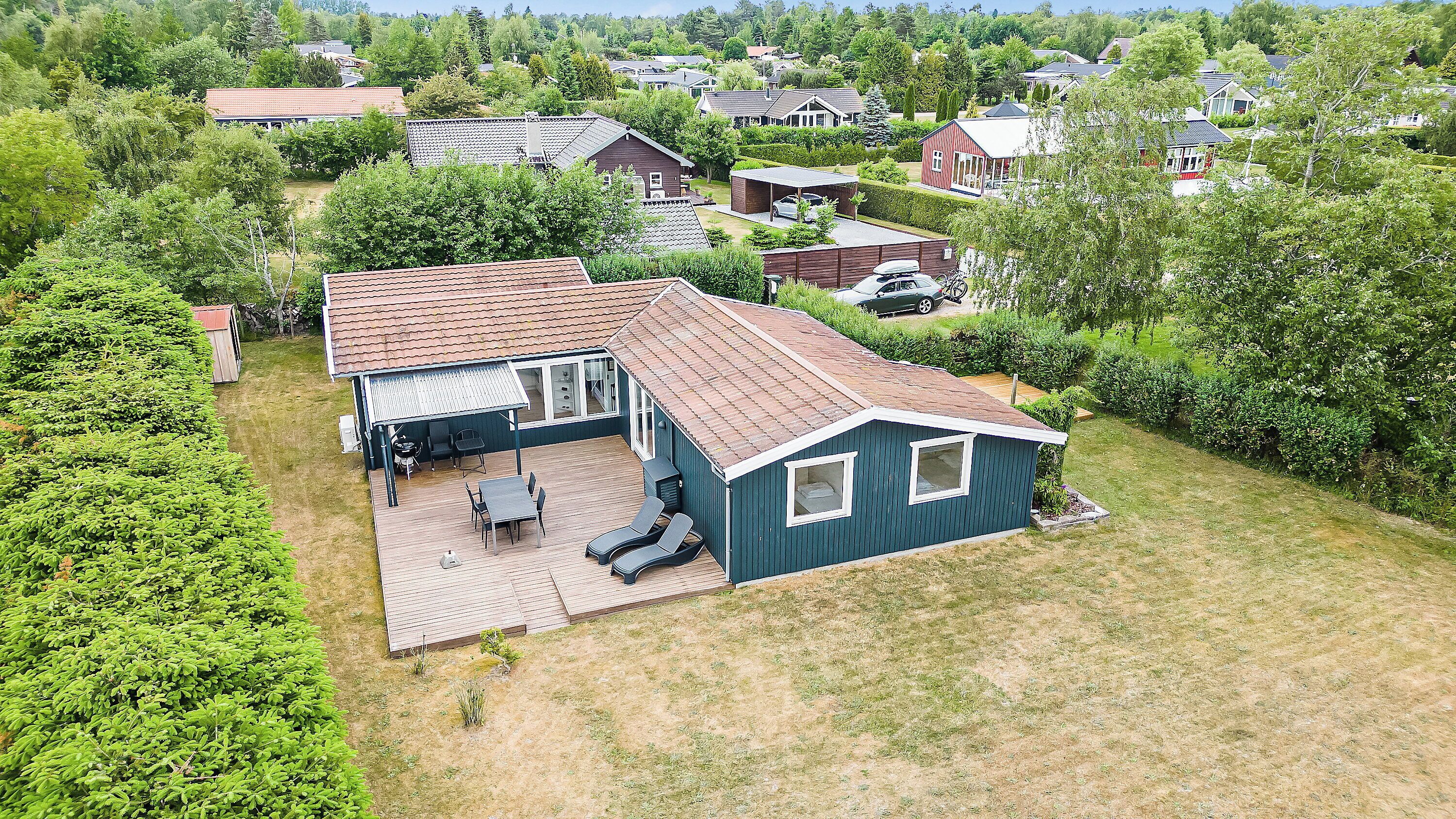 Une maison à deux étages avec un patio, un garage et un petit jardin.