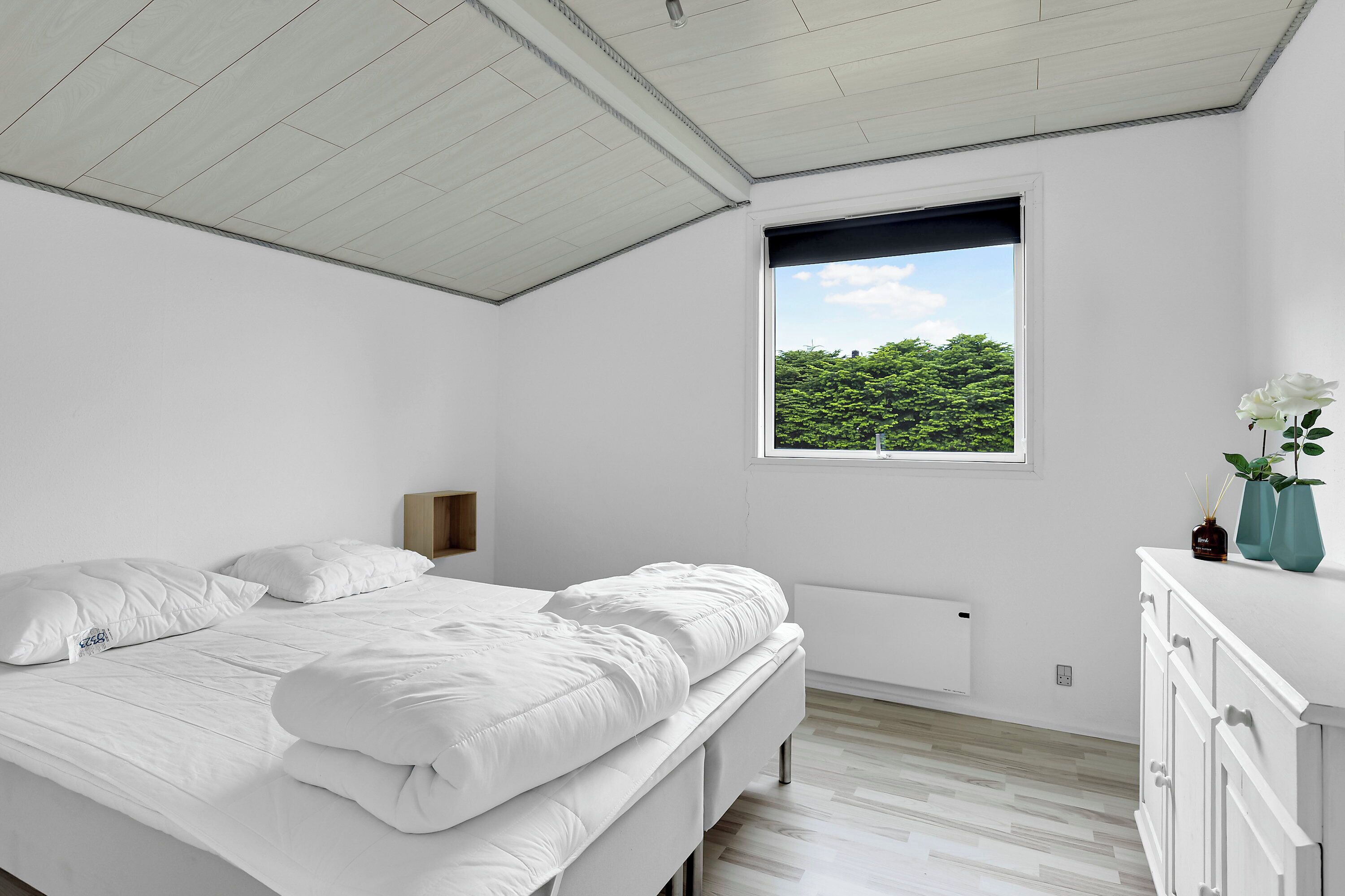 Un dormitorio con cama, ventana, radiador y cómoda.