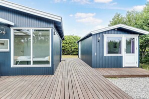 Ein modernes Gebäude mit einer Terrasse, großen Fenstern und einer Tür.