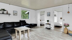 Ein modernes Wohnzimmer mit einem schwarzen Ledersofa, einem Holztisch und einem großen Fenster.