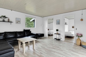 Un salon moderne avec un canapé en cuir noir, une table basse en bois et une grande fenêtre.