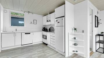 Une cuisine moderne avec des meubles blancs, un four encastré et une fenêtre donnant sur un espace verdoyant.