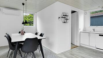 Et moderne køkken med hvide skabe, en indbygget opvaskemaskine og et vindue med udsigt til grønne områder.