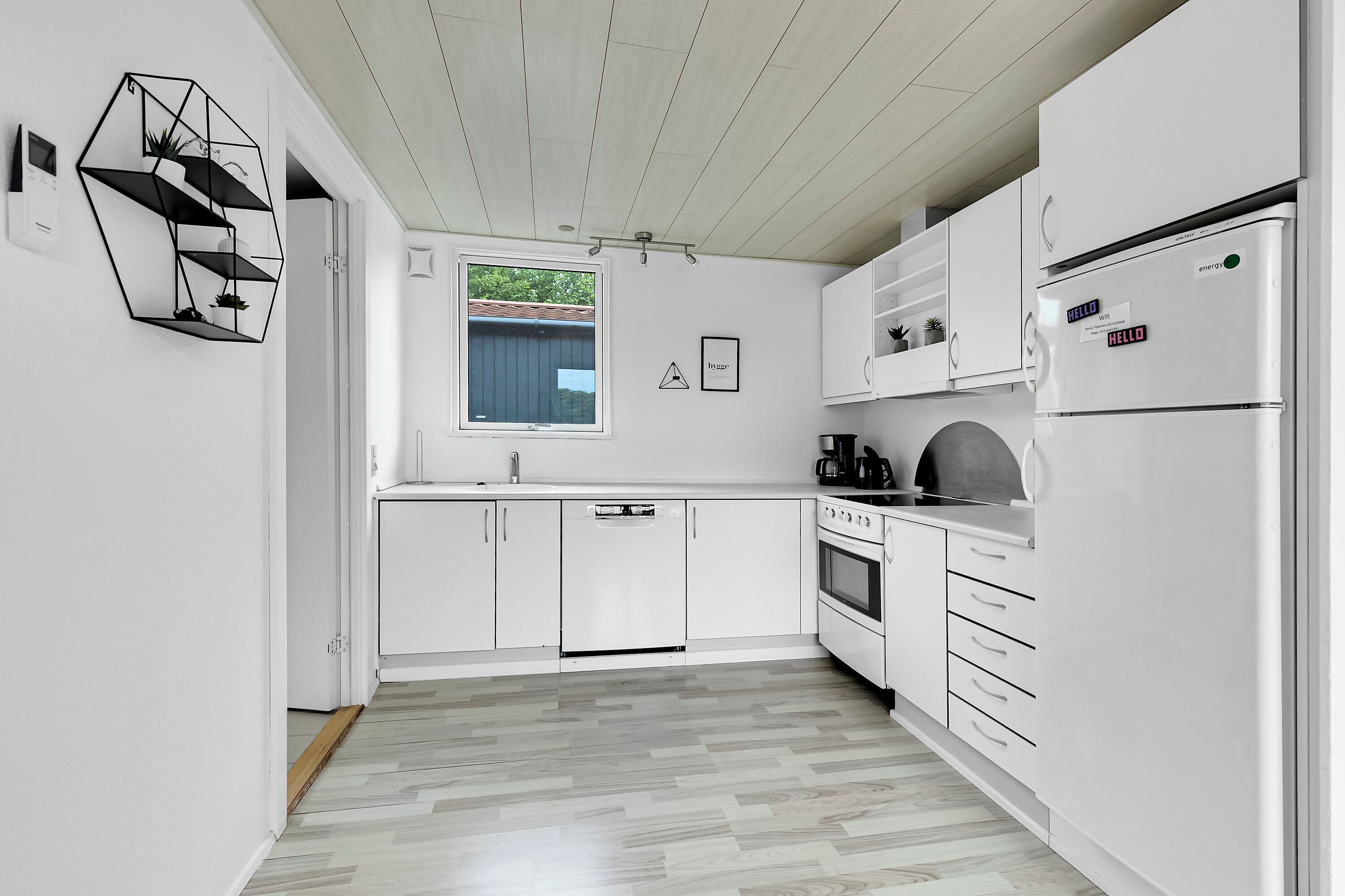A modern kitchen with white cabinetry, a built-in oven, and a refrigerator.