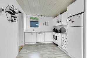 Une cuisine moderne avec des meubles blancs, un four encastré et un réfrigérateur.