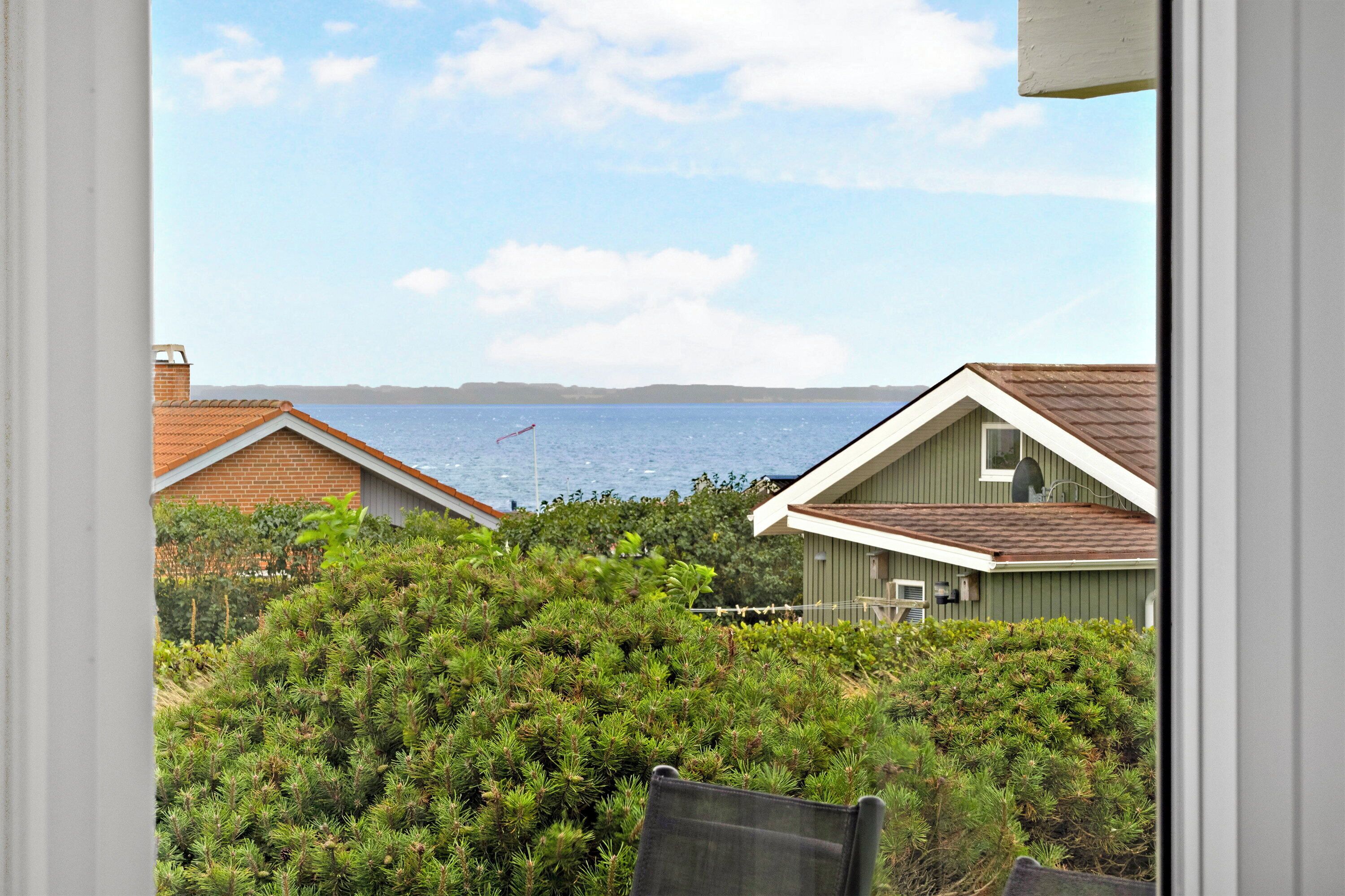 Blick auf eine Küstenlandschaft mit Häusern, Wasser und blauem Himmel.