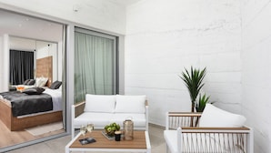 Een moderne hotelkamer met een bed, een bank, een klein tafeltje met drankjes en een plant.