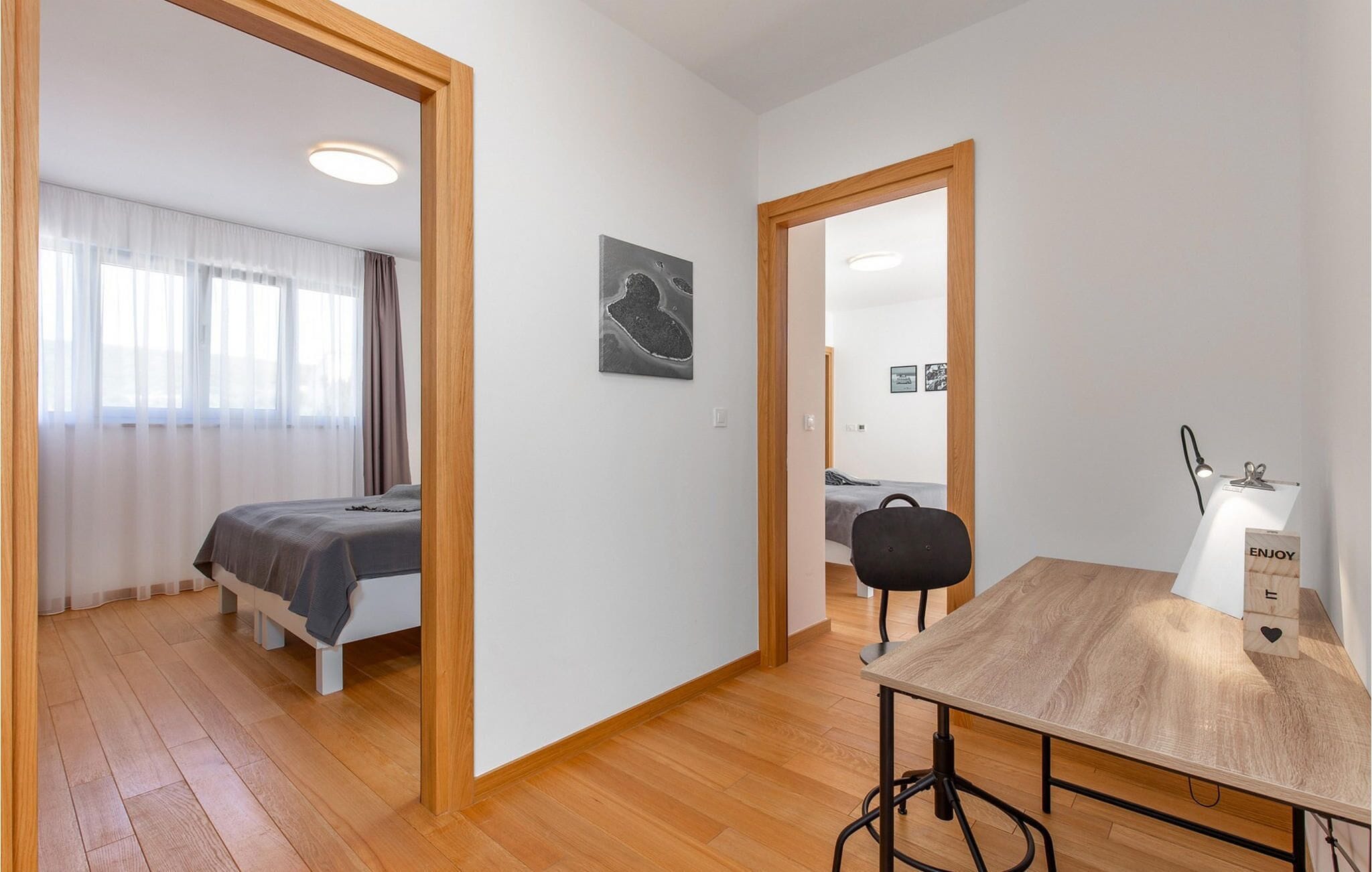 A modern, well-lit room with a bed, a desk with a lamp, and a chair.