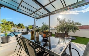 An outdoor patio with a glass table and chairs, a small pool, and potted plants. - Beach front home in Razanj (Razanj)