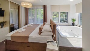 A modern bedroom with a large bed, a built-in jacuzzi, and a balcony with a view of greenery. - Luxurious home in Zaton with sauna (Zaton)