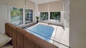 A modern living room with a glass-top pool, large windows, and a view of greenery outside. - Luxurious home in Zaton with sauna (Zaton)