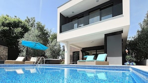 A modern two-story building with a swimming pool, lounge chairs, and a blue umbrella. - Luxurious home in Zaton with sauna (Zaton)