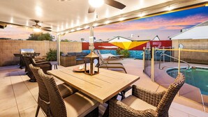 Eine Außenpatio mit Pool, Deckenventilatoren und einem Tisch mit Stühlen.
