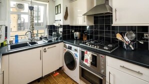 Une cuisine de taille réduite équipée d’un lave-linge, d’une cuisinière et d’un évier.