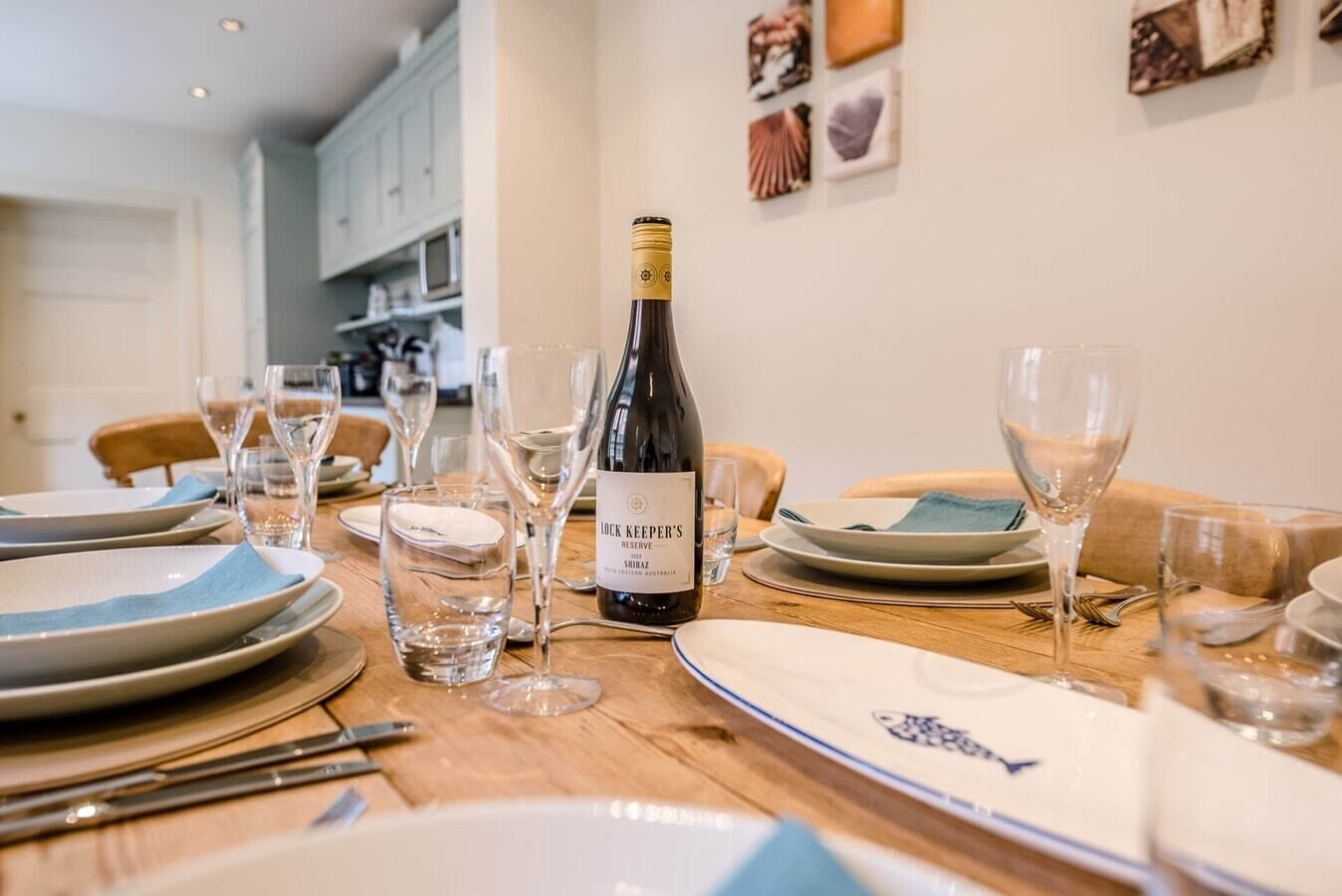 Una mesa de comedor dispuesta con platos, vasos y una botella de Shiraz Lock Keeper's Reserve.