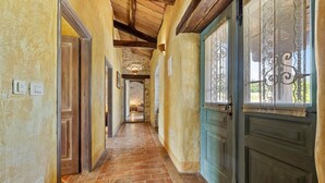 Un pasillo con suelo de ladrillo, puertas de madera y pared de piedra.