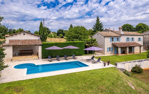 A residential property with a swimming pool, outdoor seating, and stone buildings.