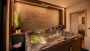 Une salle de bain moderne avec un mur en pierre, un jacuzzi et un miroir.