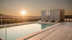 Une piscine avec des chaises longues et une vue sur le coucher de soleil.