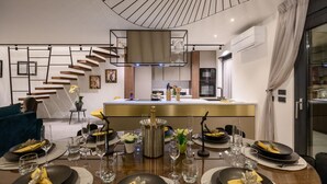 Un espace de repas moderne avec un îlot central, un escalier et une cuisine en arrière-plan.