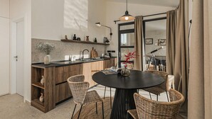 Una cucina moderna con isola centrale, mobili in legno e zona pranzo con sedie in vimini e un tavolo rotondo.