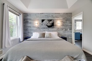 Une chambre avec un grand lit, un mur en bois et deux lampes fixées au mur.