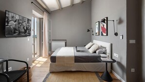 Camera da letto moderna con un letto grande, una scrivania e una sedia. Si vede una finestra con vista all'esterno.