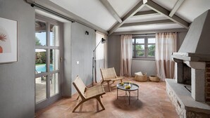 Una zona patio accogliente con sedie in vimini, un tavolo rotondo con bevande e un camino in pietra.
