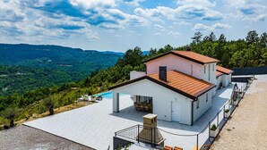 Una villa moderna con piscina, rodeada de exuberante vegetación y montañas.