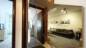 Una sala de estar moderna con un espejo grande que refleja el ambiente, un sofá y decoración en la pared.