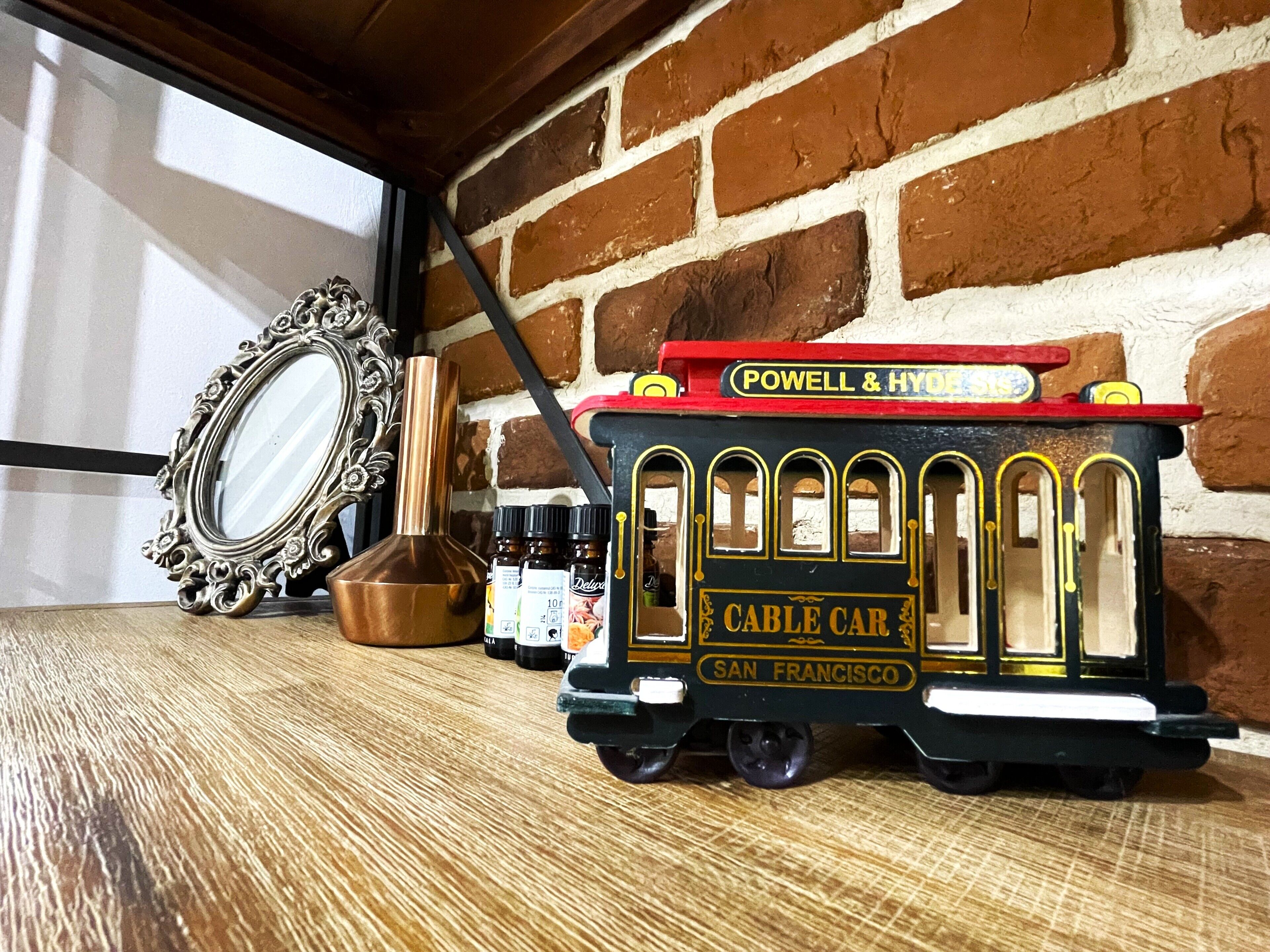 A model cable car labeled "Powell & Hyndman" on a wooden surface with a mirror and bottles.