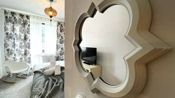 Ein Schlafzimmer mit einem Bett, einem Schaukelstuhl, einem an der Wand montierten Fernseher und einer dekorativen Deckenleuchte.