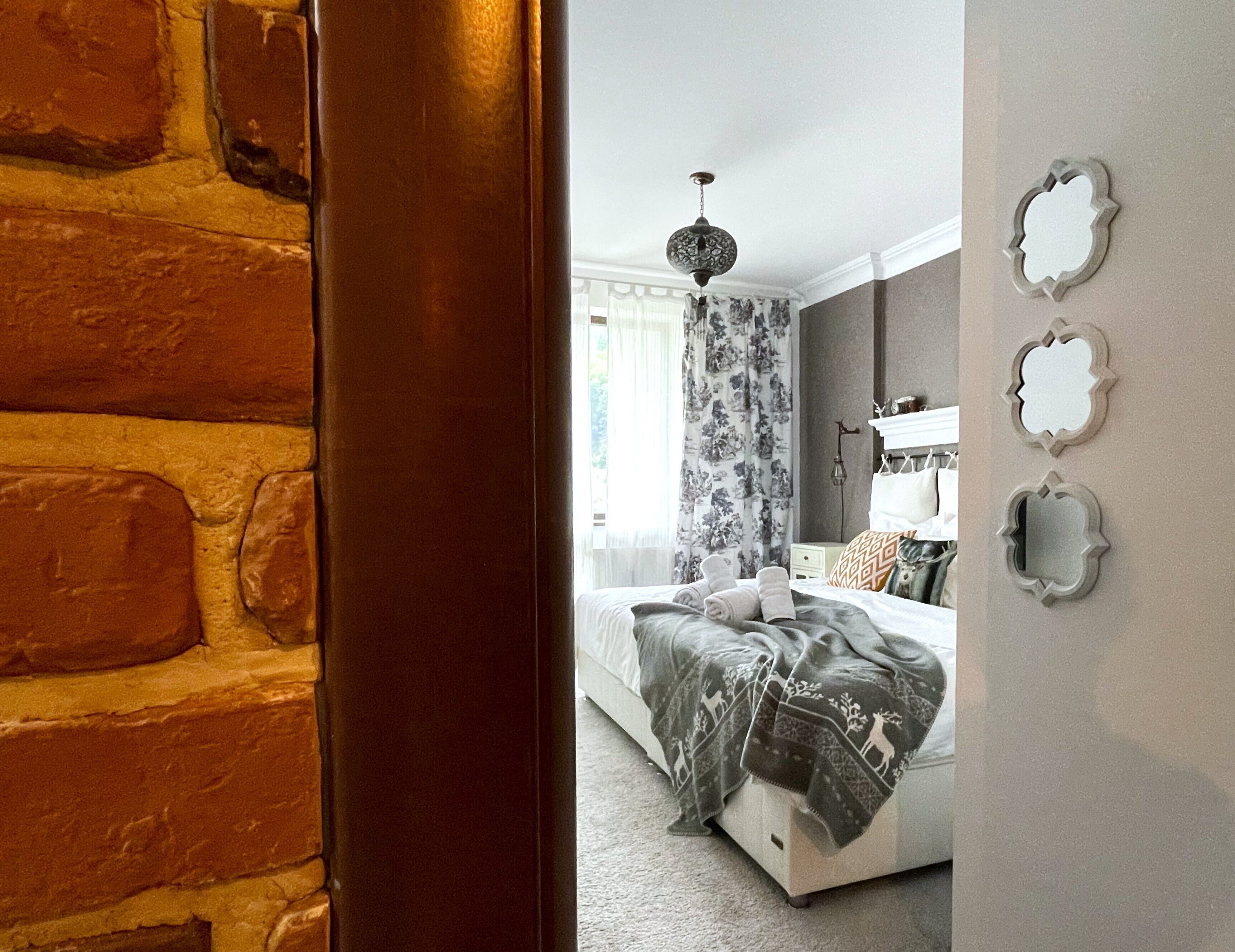 A bedroom with a bed, a nightstand, a lamp, and a window with curtains.