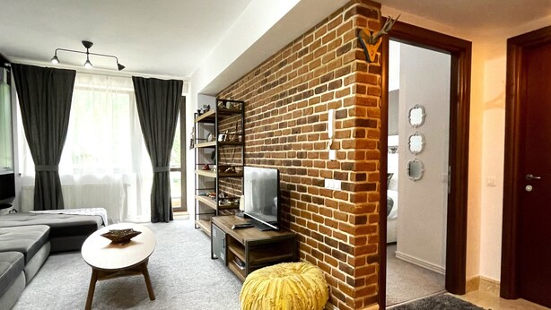 Una sala de estar moderna con una pared de ladrillo decorativa, un sofá, una mesa de centro, un televisor y una estantería.