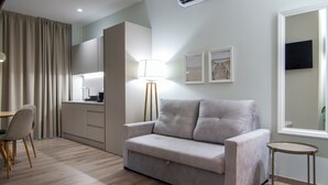 Un salon moderne comprenant un canapé, une table à manger avec des chaises, une lampe et un coin cuisine.
