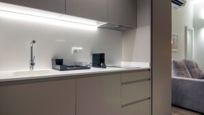 Une cuisine moderne équipée d’un évier encastré, d’une machine à café et d’un petit boîtier noir posé sur le plan de travail.