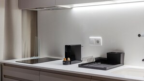 A modern kitchen with a white countertop, a black induction cooktop, a coffee maker, and a black coffee grinder. - VLC HOST - Reino 4 (Valencia)