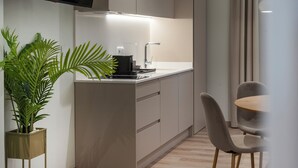 Una cocina moderna con estufa incorporada, un lavamanos y una zona de comedor con mesa y sillas.
