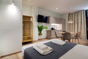 Een hotelkamer met een bed, een bureau, een stoel, een televisie en een plant.